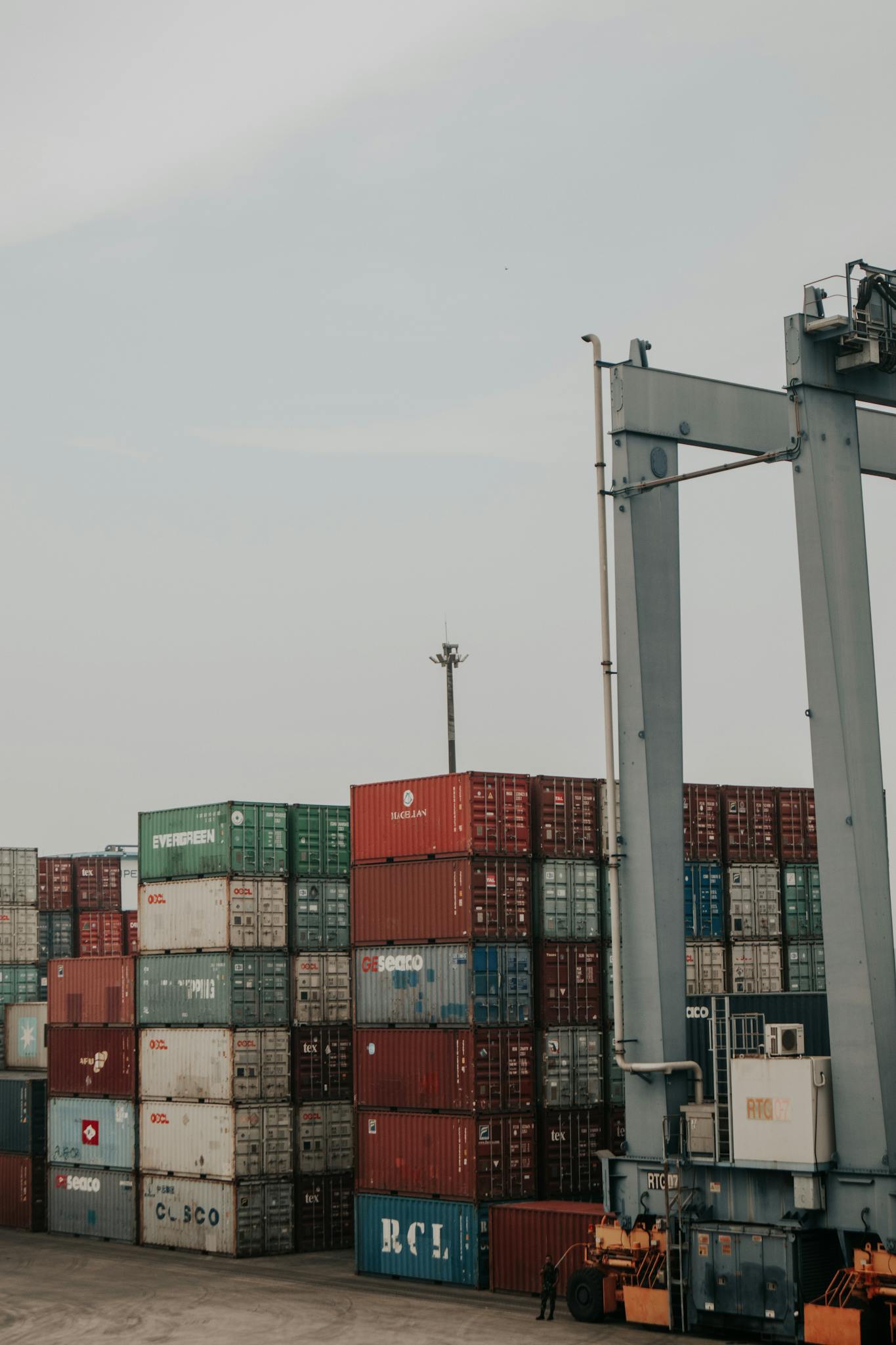 Vertical shot of a busy cargo port with stacked shipping containers under a gray sky.